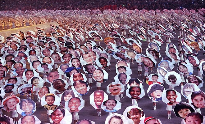 Crianças defilam com painéis com faces de crianças de diversas etnias |