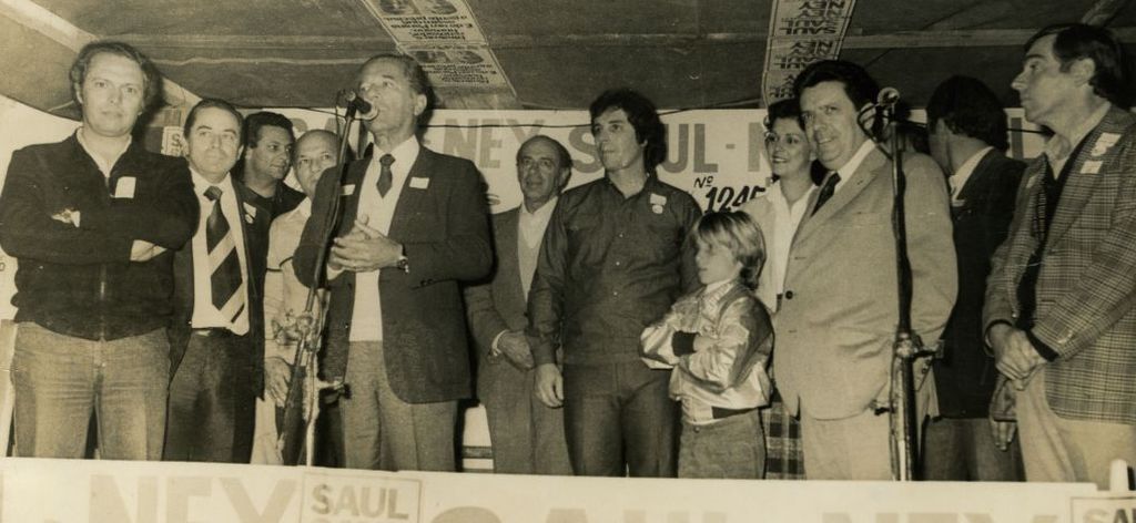 O menino Fábio Camargo, ao lado do pai (camisa escura), ouve discurso do ex-governador Ney Braga na campanha eleitoral de 1982 | Arquivo pessoal de Fabio Camargo