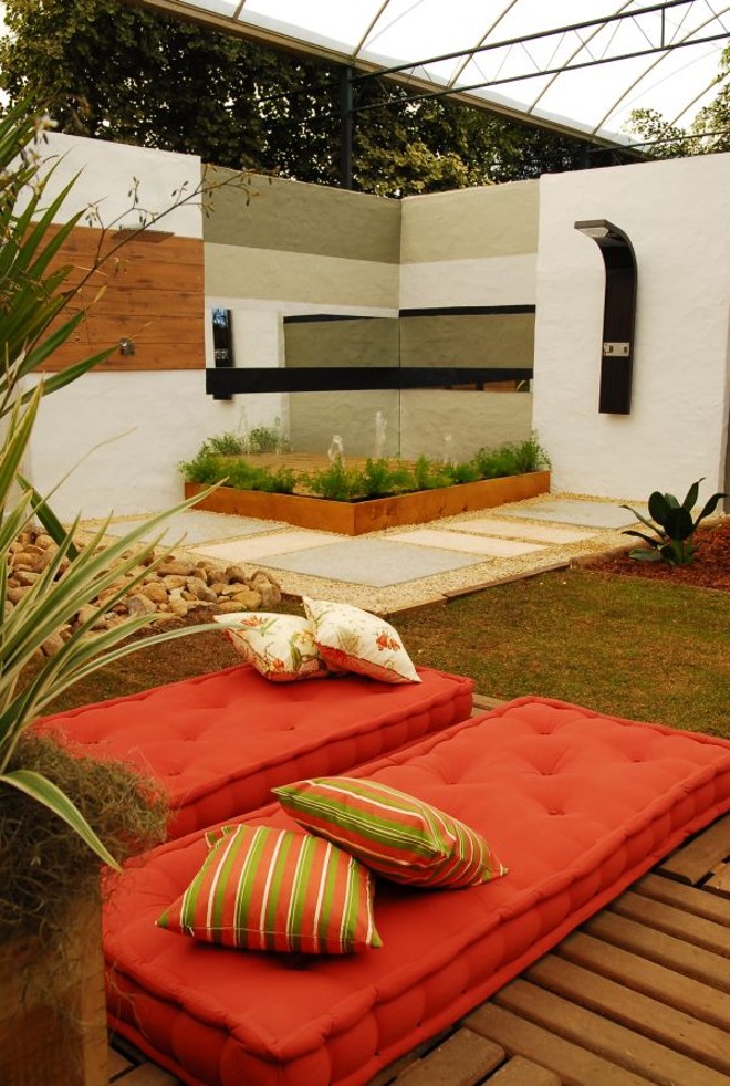 Ideal para relaxar: Uma ducha em aço inox e madeira, colocada na parede quase como uma escultura, e jatos que saem do chão, são os destaques do ambiente Ducha e Jardim, dos arquitetos Mirella Sanches, José Grieco e Raquel Alves. O espaço tem plantas como o pandanus (que cresce em espiral) e areca (com caule dourado) |