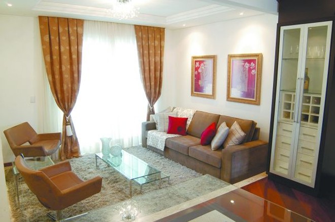 Espaço do home theater traz o constraste entre a madeira escura e os estofados brancos |