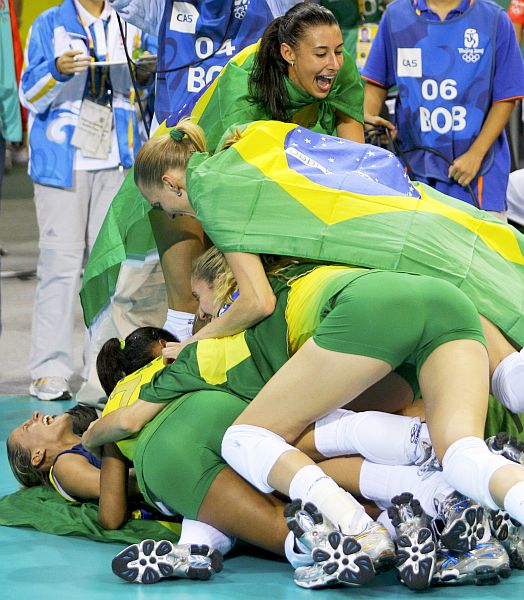 Mari (com a bandeira nas costas) engrossa o bolinho das jogadoras na quadra, logo após a decisão: na coletiva, a oposto emprestou sua medalha para Zé Roberto Guimarães. | Alexander Demanchiuk/ Reuters