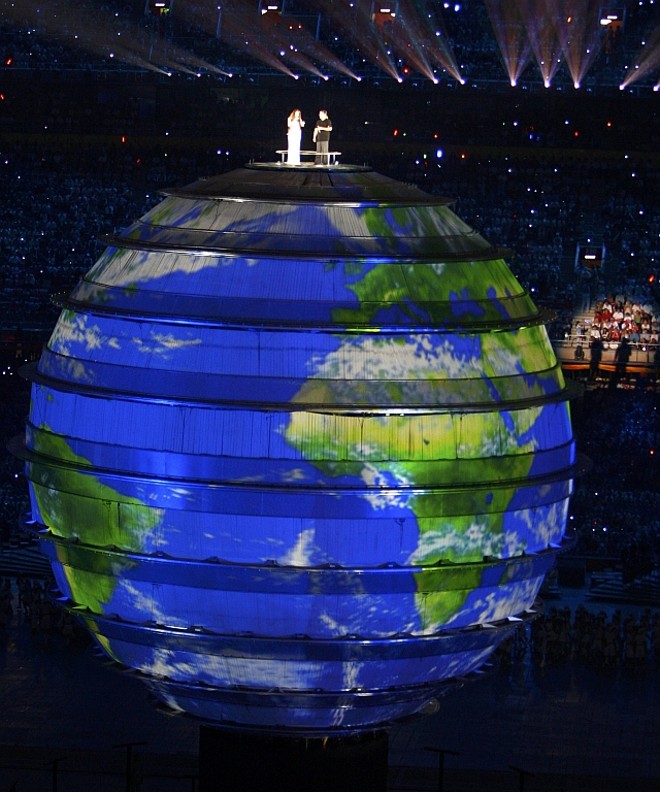 O cantor chinês Liu Huan e a britânica Sarah Brightman cantam a música tema dos Jogos no alto do globo terrestre |