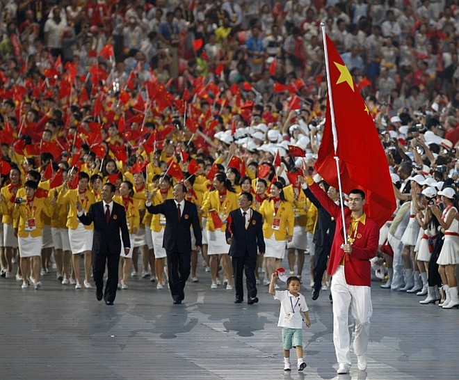 Yao Ming - com a bandeira chinesa - é acompanhado por Lin Hao - menino de nove anos que sobreviveu ao terremoto de Sheniang, em maio passado |