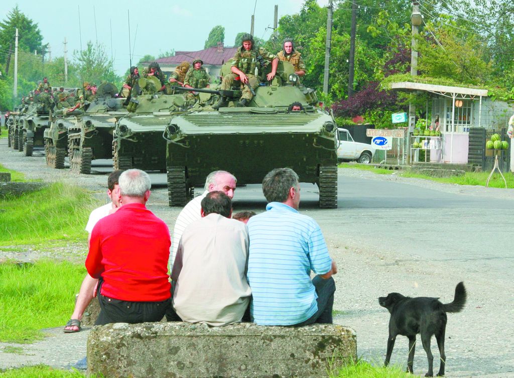 Moradores da cidade de Zugdidi, no oeste da Geórgia, observam comboio militar russo atravessar a cidade | Umit Bektas/Reuters