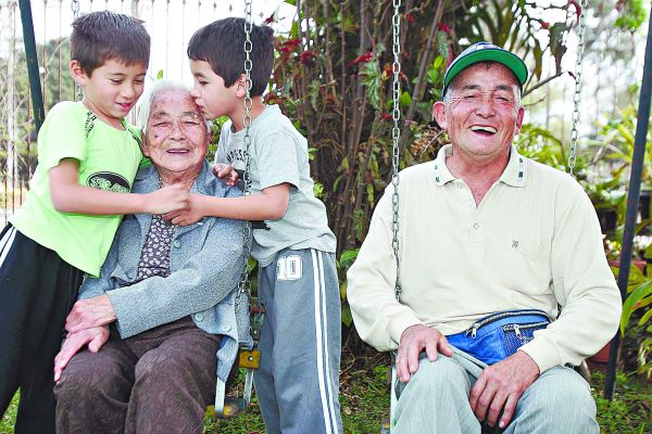 A bisavó recebe o carinho de Caio Satoshi Kosaka (esquerda) e Hugo Toschio Kosaka: geração preservada. | Daniel Castellano/Gazeta do Povo