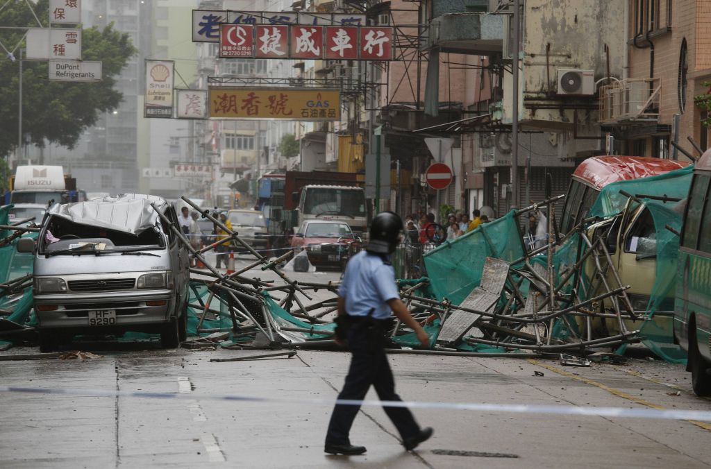 Policial caminha em meio a veículos destruídos. Perdas materiais foram ocasionadas pela passagem da tempestade Nuri | Bobby Yip / Reuters