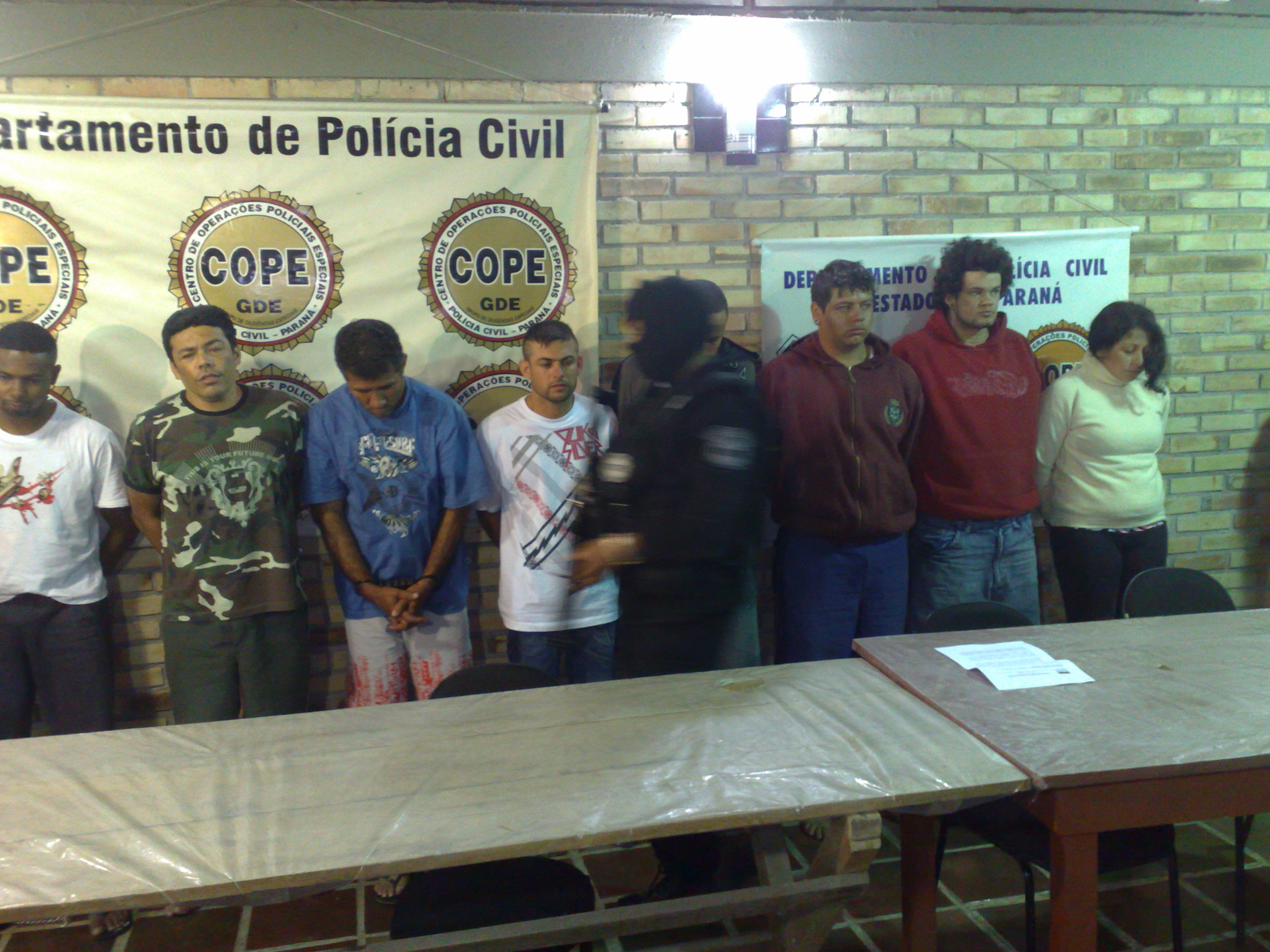 POlicial passa diante dos oito presos por roubar pelo menos quatro agências bancárias do Paraná | João Varella / Gazeta do Povo