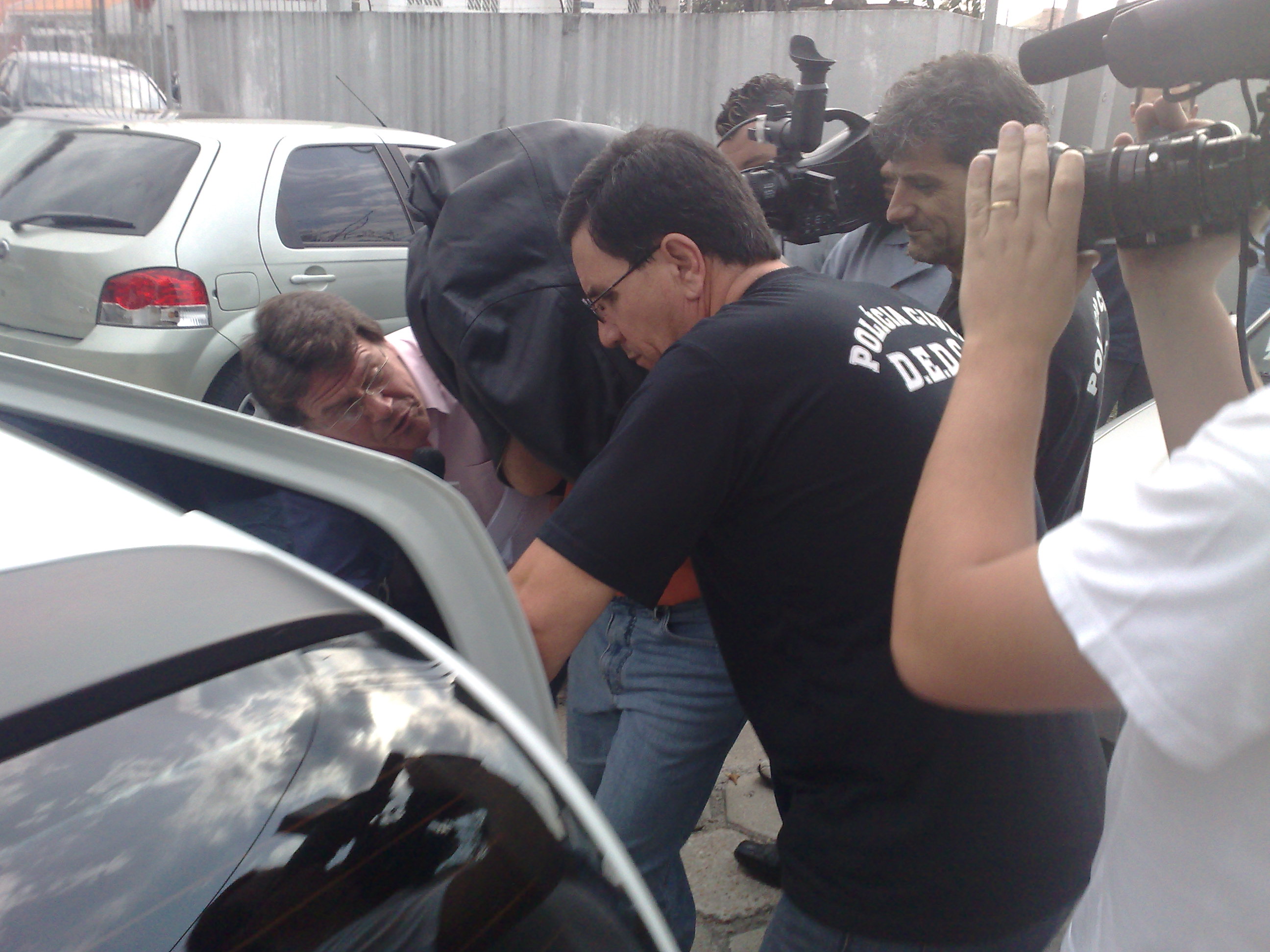 O candidato Walter Tenan, com a cabeça coberta por uma jaqueta de couro preta, no momento em que entrava no carro que o levaria à prisão | João Varella / Gazeta do Povo