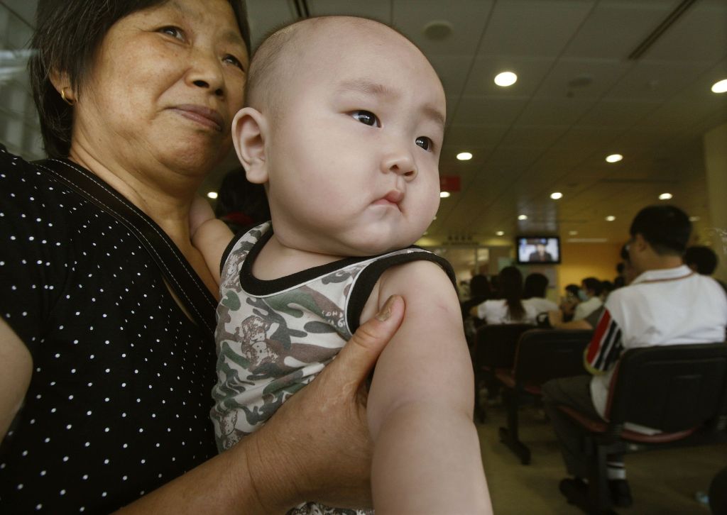 Mãe segura bebê num centro de emergência: crianças estão sendo analisadas, com suspeita de terem bebido leite com o químico melamina | Bobby Yip / Reuters