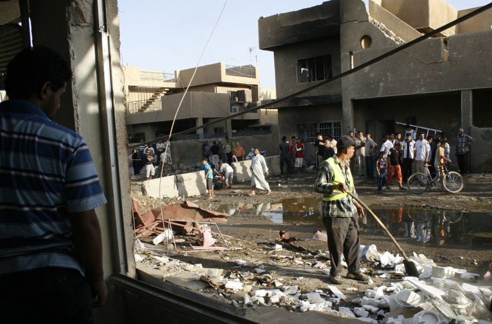 Gari iraquiano remove destroços provocados pela explosão de um carro-bomba próximo de um complexo empresarial, em Karradah | Bassim Shati / Reuters
