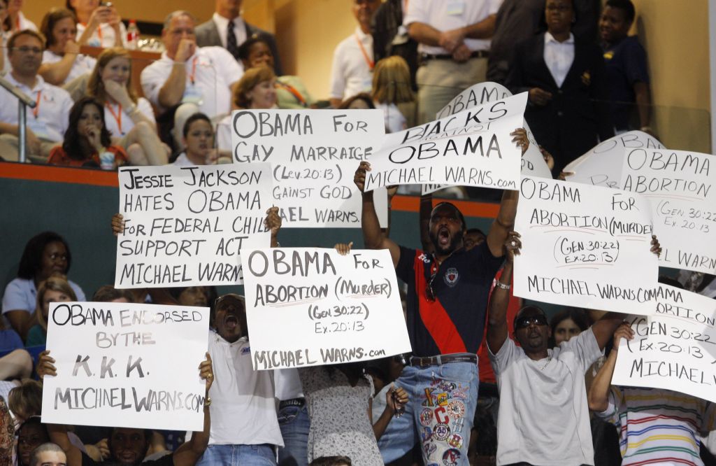 Jovens negros seguravam cartazes apregando que Obama é contra os afro-americanos | Carlos Barria / Reuters
