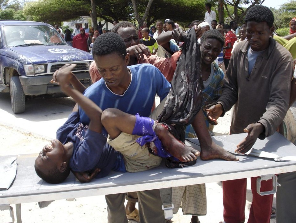 Garoto é carregado de maca após sofrer ferimentos provocados por projéteis, que atingiram o centro de comércio, na capital Mogadishu: "Vimos quatro pessoas morrerem na hora. A carne e o sangue foram espalhados aos pedaço", relatou o vendedor de roupas Nur Omar | Mowlid Abdi / Reuters