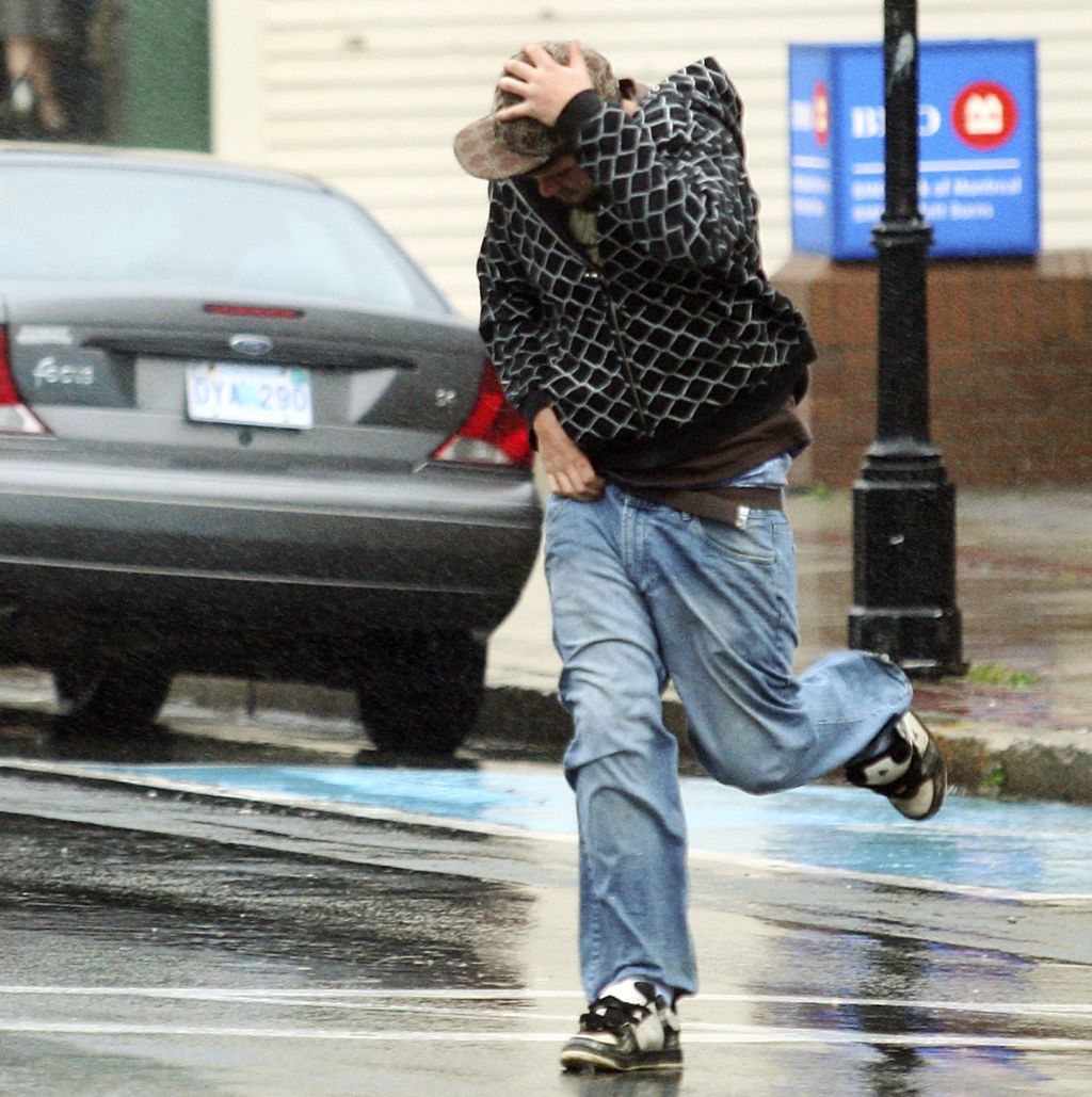 Jovem protege-se da força dos ventos entre 80 e 100 quilômetros, apesar do rebaixamento de Kyle para tempestade | Paul Darrow / Reuters