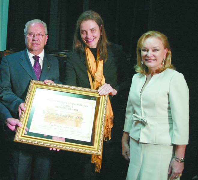 A jornalista Ana Amélia Filizola, vice-presidente da Rede Paranaense de Comunicação, recebeu no último sábado das mãos da presidente do Instituto Histórico e Cultural da Lapa, Maria Inês Borges da Silveira (à dir.), a inédita comenda Tropeiro da Lapa, concedida a seu pai, o jornalista Francisco Cunha Pereira Filho, diretor-presidente da Gazeta do Povo e da RPC. Também na foto, o ex-ministro Luiz Carlos Borges da Silveira | 