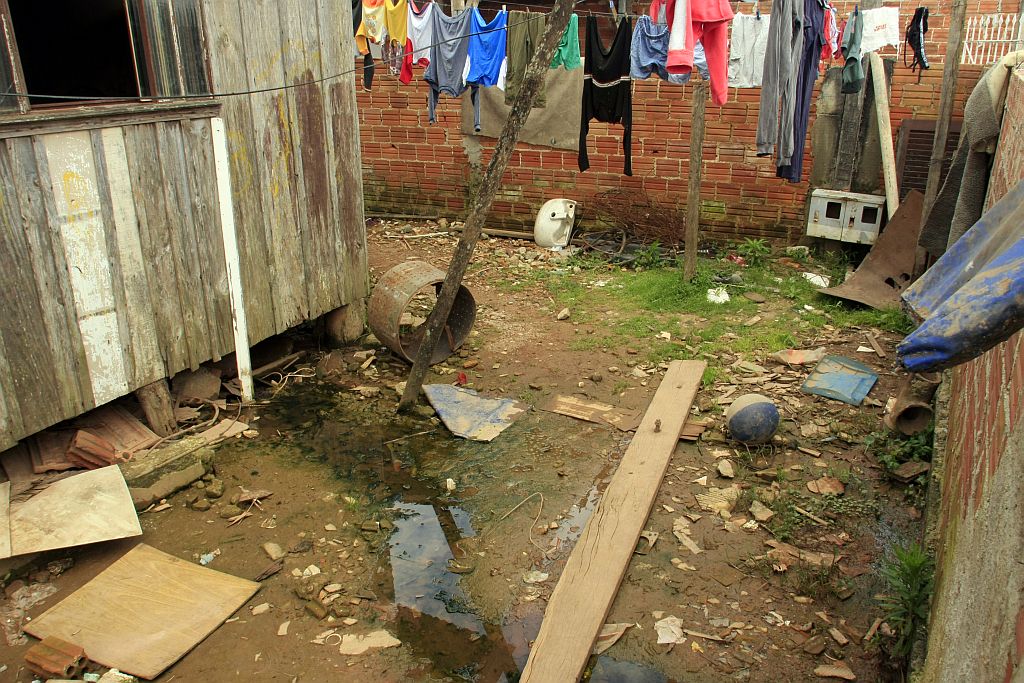 Moradores improvisam ponte sobre o esgoto que corre entre as casas na Vila Osternack | Daniel Derevecki/Gazeta do Povo