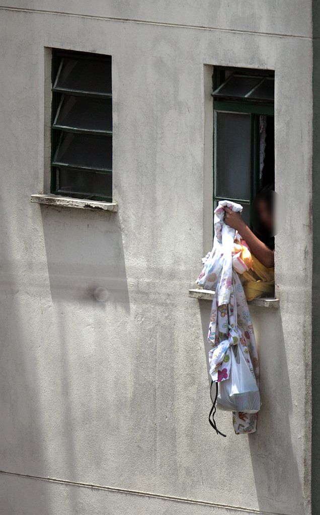 Eloá aparece na janela do apartamento para puxar uma marmita com uma corda feita de lençóis | Robson Fernandes/AE