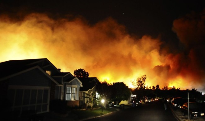 Incêndio é visto atrás de um conjunto residencial em Sylmar, na Califórnia: pelos menos duas pessoas morreram | Gene Blevins/Reuters