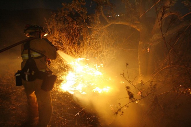 Bombeiro apaga foco de incêndio: três focos já queimaram 88 quilômetros quadrados no sul da Califórnia | Mario Anzuoni / Reuters