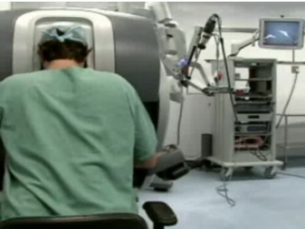 Médico opera o sistema robótico cirúrgico, permitindo operar os braços mecânicos do robô com um videogame | Reprodução / G1