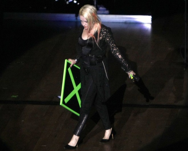 Cyndi entra no palco segurando uma placa e um martelo | 