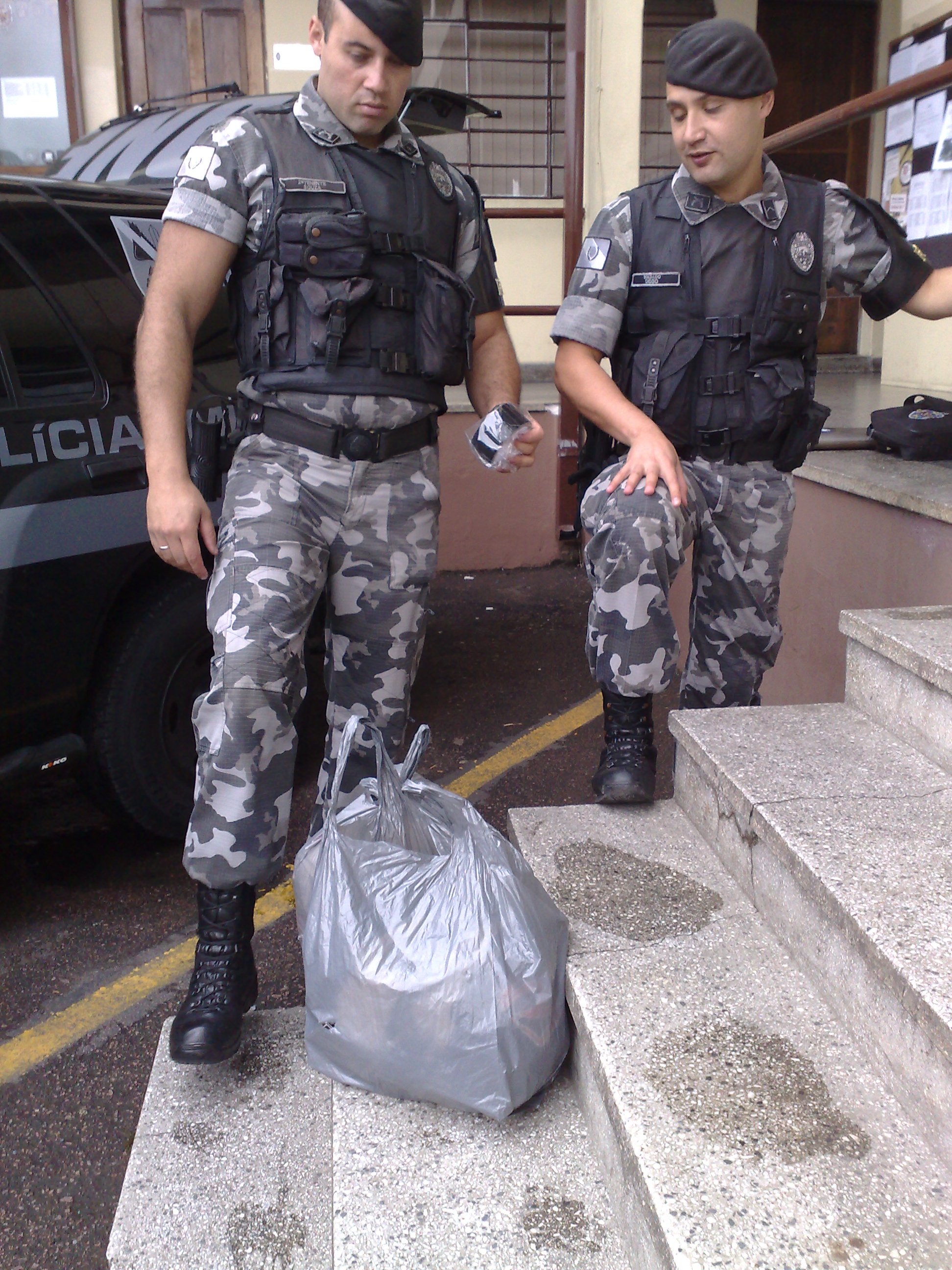 O tenente Luciano Martins de Souza observa sacola com os objetos recuperados da loja de surf assaltada nesta manhã | João Varella/Gazeta do Povo