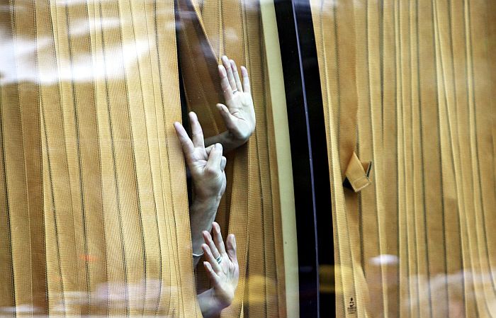 Hóspedes do Hotel Trident, em Mombai, na Índia, fazem o símbolo da vitória após a retirada dos terroristas invasores | Pal Pillai/AFP