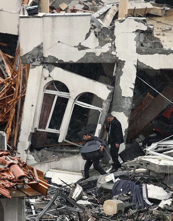 Palestino carrega televisão em frente a uma construção destruída pelos ataques de Israel, em Gaza | Suhaib Salem/Reuters