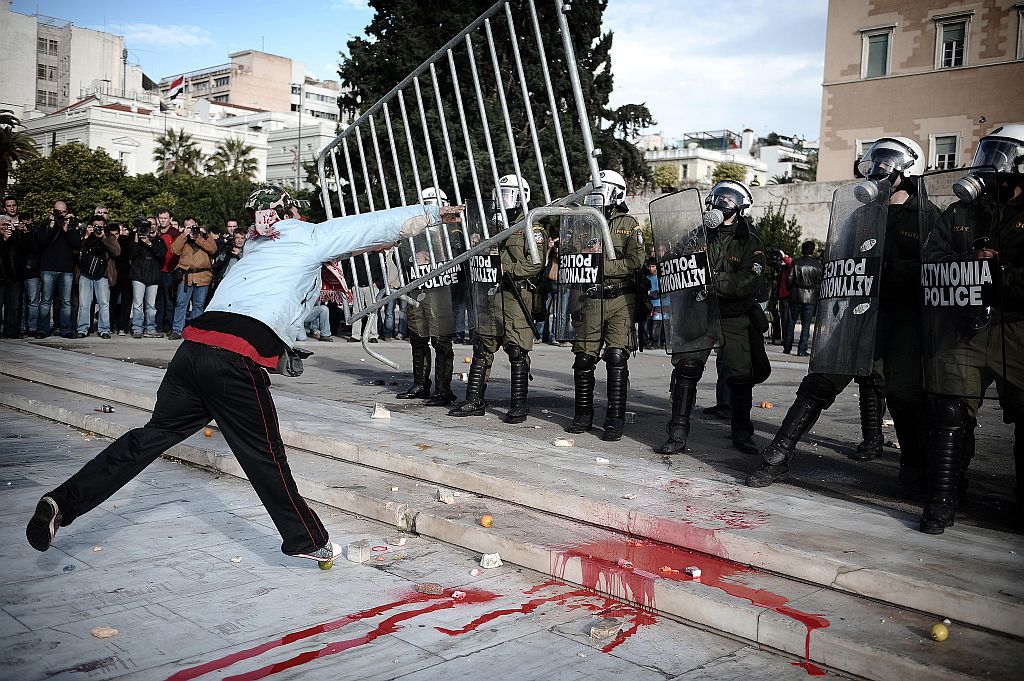 Jovem joga barricada de ferro contra policiais, em Atenas: estudantes pedem a saída do primeiro-ministro, Costa Karamanlis | Olivier Laban-Mattei/AFP