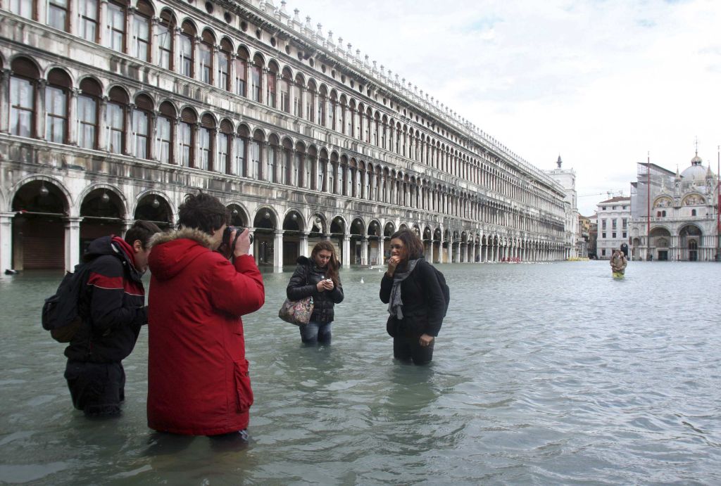 Turistas visitam a Praça São Marcos, no centro histórico de Veneza, mesmo com água acima dos joelhos | Manuel Silvestri/Reuters