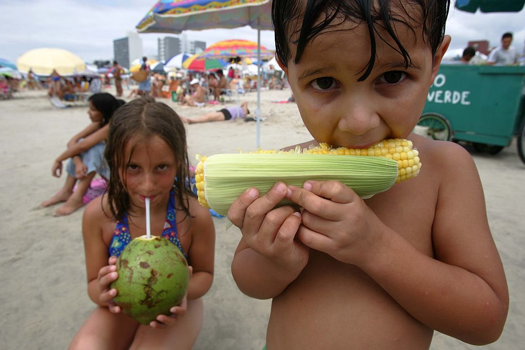 Mateus, 4 anos, e Gabriele Fávaro Cassiano, 8 anos, se deliciam com o milho verde e a água de coco, boas opções de lanche, segundo os especialistas | Jonathan Campos/Gazeta do Povo