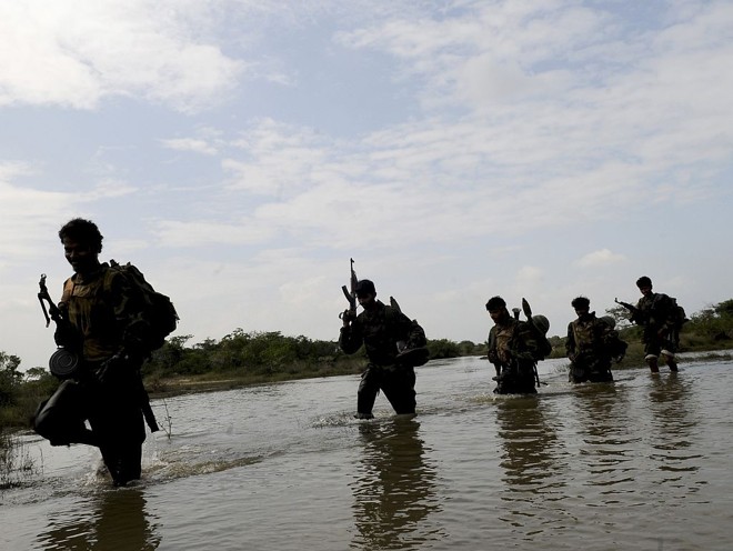 Soldados do Sri Lanka caminham num lago na recente captura da capital do país no território de Paranthan | Stringer / Reuters