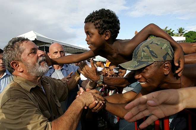 Lula cumprimenta populares durante visita ao município de Lauro de Freitas, na Bahia, para inauguração de residências do projeto Habitar Brasil, em janeiro de 2003. | 