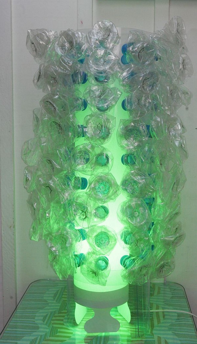 A luminária Vita Light recebeu a aplicação de cerca de 100 garrafas pet em todo o seu entorno. O trabalho é da Paper.Art | 