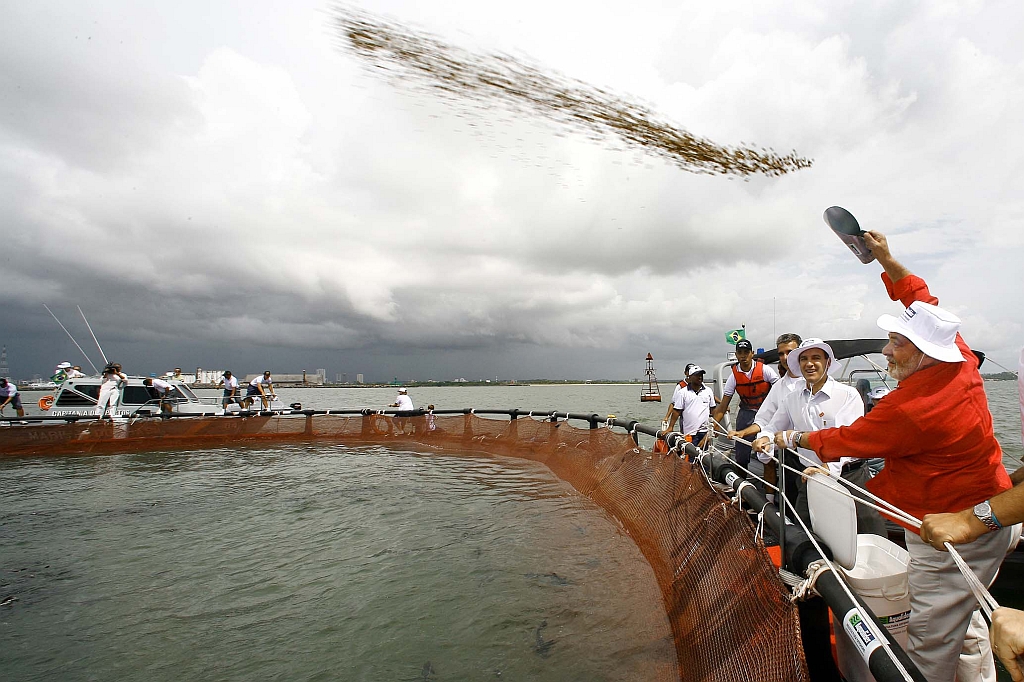 Lula joga ração para peixes em projeto de aquicultura financiado pelo governo federal, no Recife. Para o presidente, viagens de Dilma farão com que o PAC seja concluído | Ricardo Stuckert/ABr