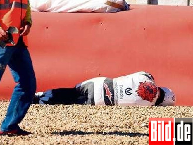Schumacher ficou caído, próximo à barreira de pneus, para desespero dos fiscais de pista |