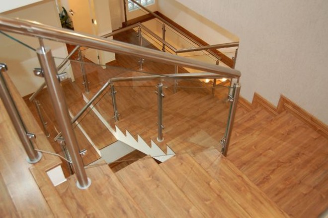 Revestimento em madeira e lateral de vidro na escada criada pela Arqtríade |