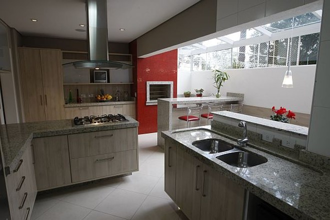 Integrada à cozinha, a churrasqueira ganha destaque com pastilhas vermelhas de vidro |