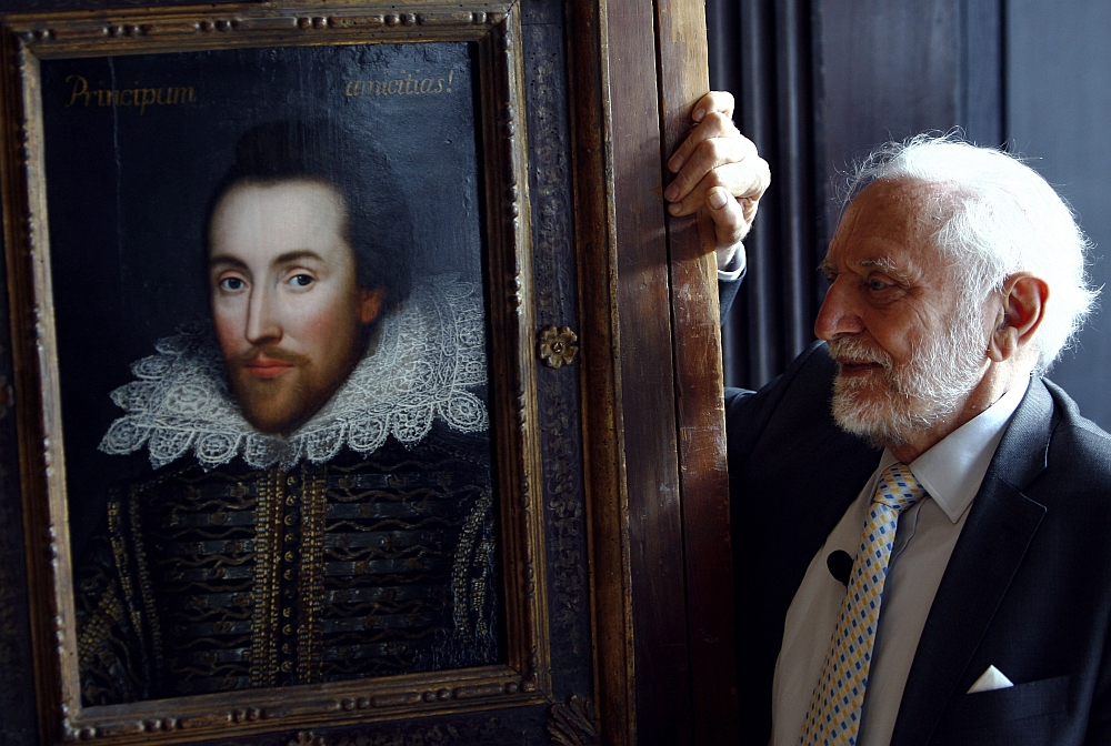 O presidente administrativo da fundação The Shakespeare Birthplace, Stanley Wells, posa ao lado do retrato de William Shakespeare em Londres | Reuters