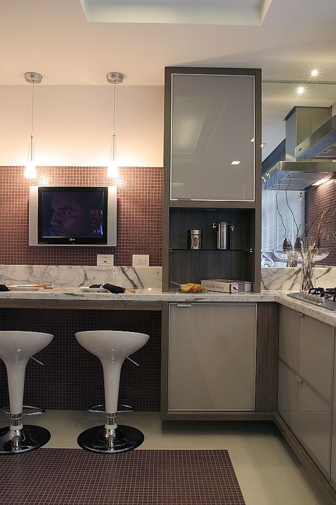 A tevê ganhou destaque no projeto de cozinha de Viviane Busch. Pastilhas de vidro vermelhas compõem o fundo |