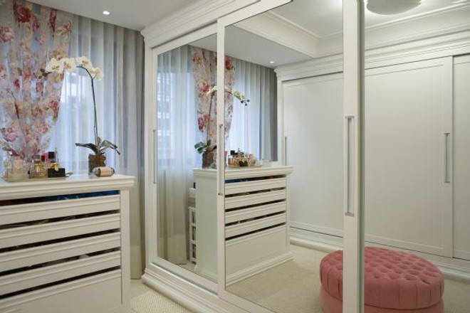 O closet mantém a laca branca da suíte e a leveza dos tecidos na organza floral e branca das cortinas | 