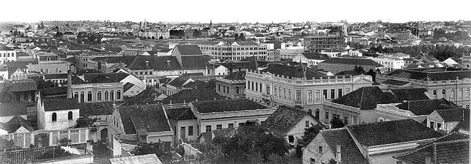 Vista parcial de Curitiba feita da torre da casa construída por José Hauer Sênior, hoje Colégio Divina Providência. A fotografia executada em 1928 mostra uma visão da cidade em direção ao sul. Em primeiro plano, podemos observar o prédio da antiga Secretaria da Fazenda, hoje Secretaria da Cultura. No plano intermediário, podemos ver o Edifício Garcez em construção | 