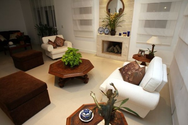 A lareira revestida em ranito bruto compõe a sala de estar do projeto assinado por Andressa Zonato |