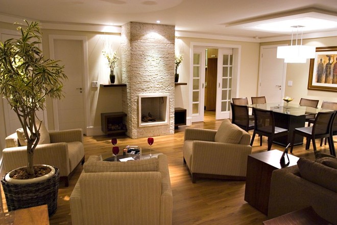 Nesse espaço, a porta de correr em madeira une e divide a sala de estar com a cozinha | 