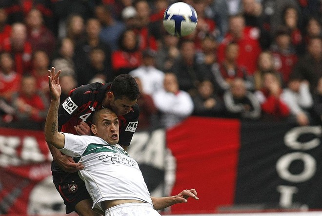 Rhodolfo ganha a disputa de bola com Ariel: enquanto o argentino saiu machucado, o atleticano tornou-se herói no segundo tempo | Rodolfo Bührer/Gazeta do Povo