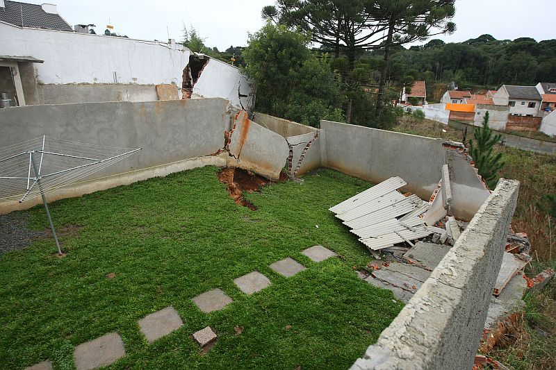 Fundos dos terrenos não suportaram o excesso de água e cederam. Churrasqueira, banheiro, canil e banheiro ficaram pendurados no barranco | Rodolfo Bührer/Gazeta do Povo
