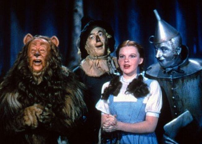 Dorothy (Judy Garland) entre seus amigos em cena de "O mágico de Oz": o leão, o espantalho e o homem de lata | Reprodução