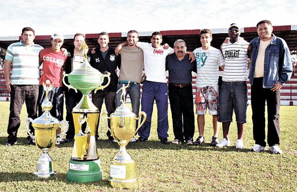 O gestor Florisval (2º a partir da esquerda), o presidente Cagnini (ao lado dele) e o técnico Nunes (à direita) com membros da comissão técnica e a coleção de troféus do Serrano | Henry Milléo/Gazeta do Povo