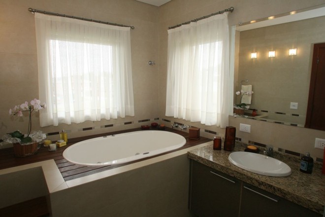 Um dos banheiros da casa possui ofurô com vista para a janela. Tons em madeira prevalecem no ambiente |