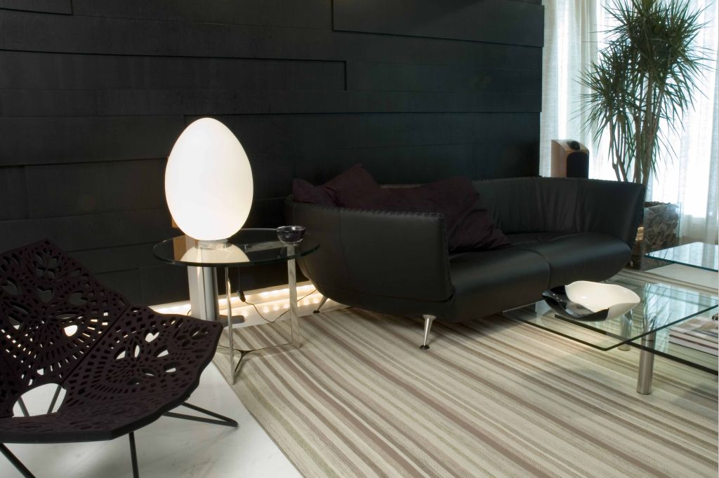 Projeto do arquiteto Ivan Wodzinsky, em que a luminária Uovo se destacou no cenário com sofá, parede e poltrona em tons escuros | Divinas Criaturas/Divulgação