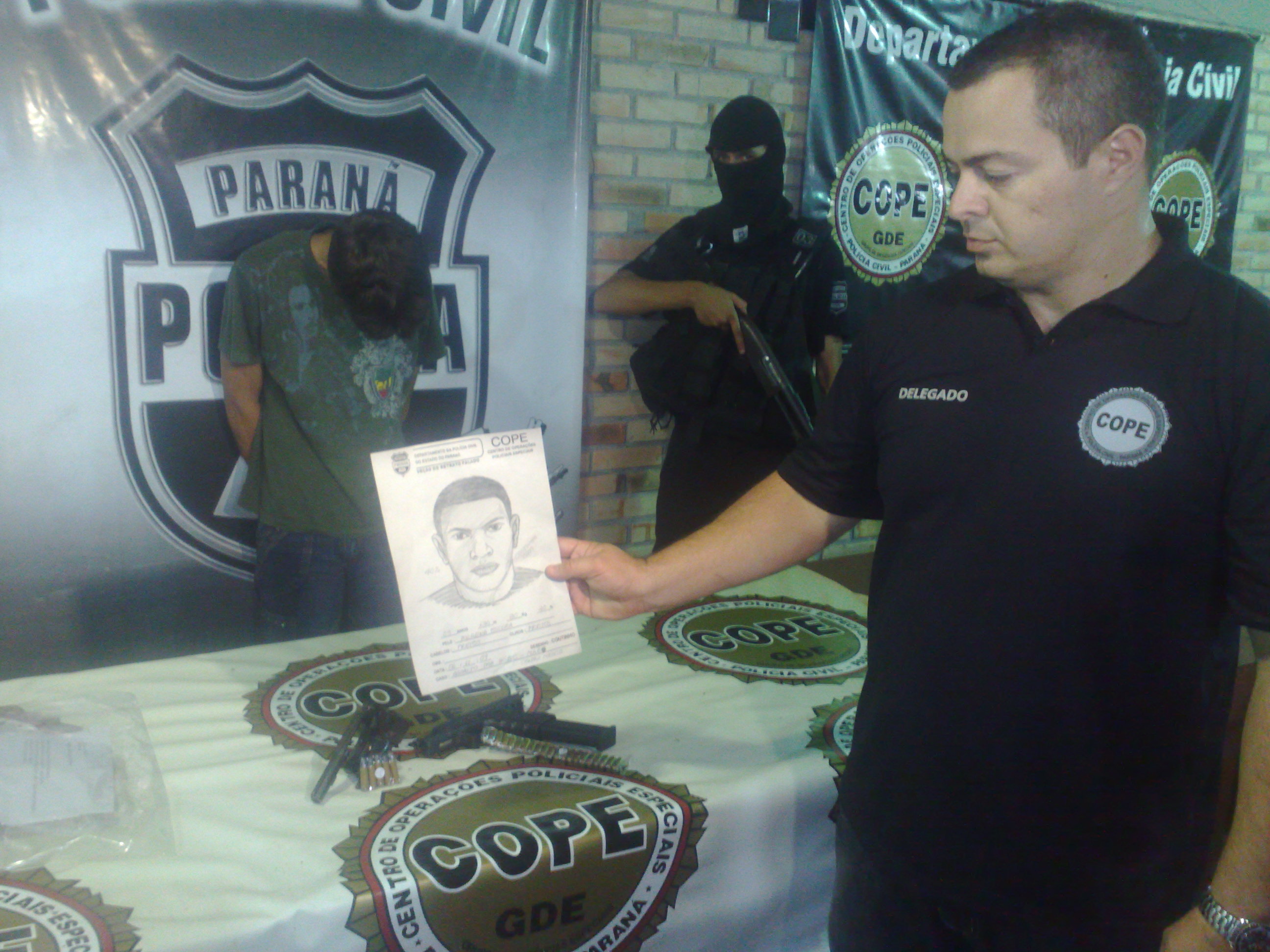 Delegado Alexandre Bonzatto, do Cope, com o retrato falado de um homem acusado de assaltar um posto bancário. Ao fundo, outro suspeito pelo mesmo crime que foi detido pela polícia | Adriano Ribeiro / Gazeta do Povo